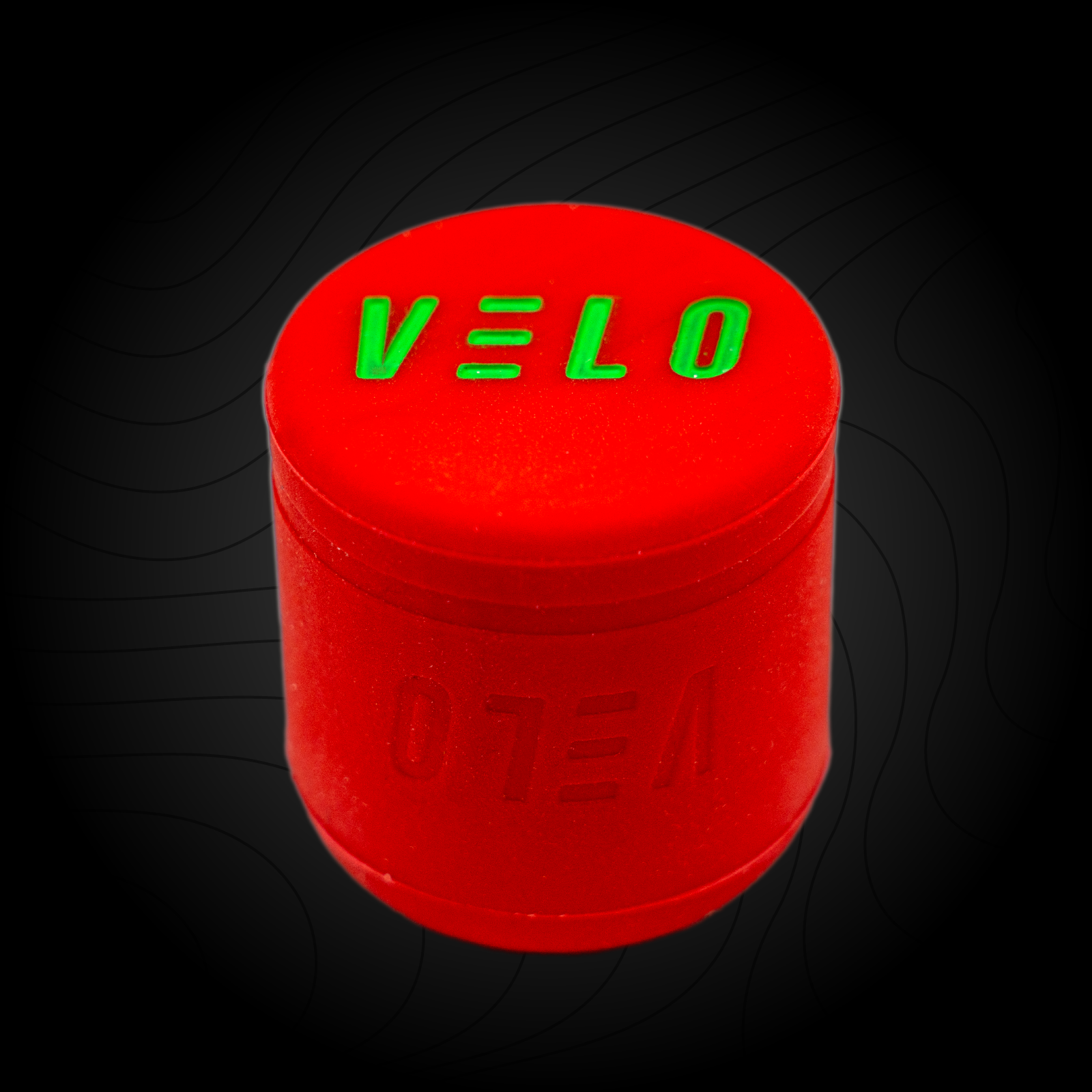 A red VELO baseball puck knob attachment with the brand name 'VELO' written in green letters on the bottom surface.