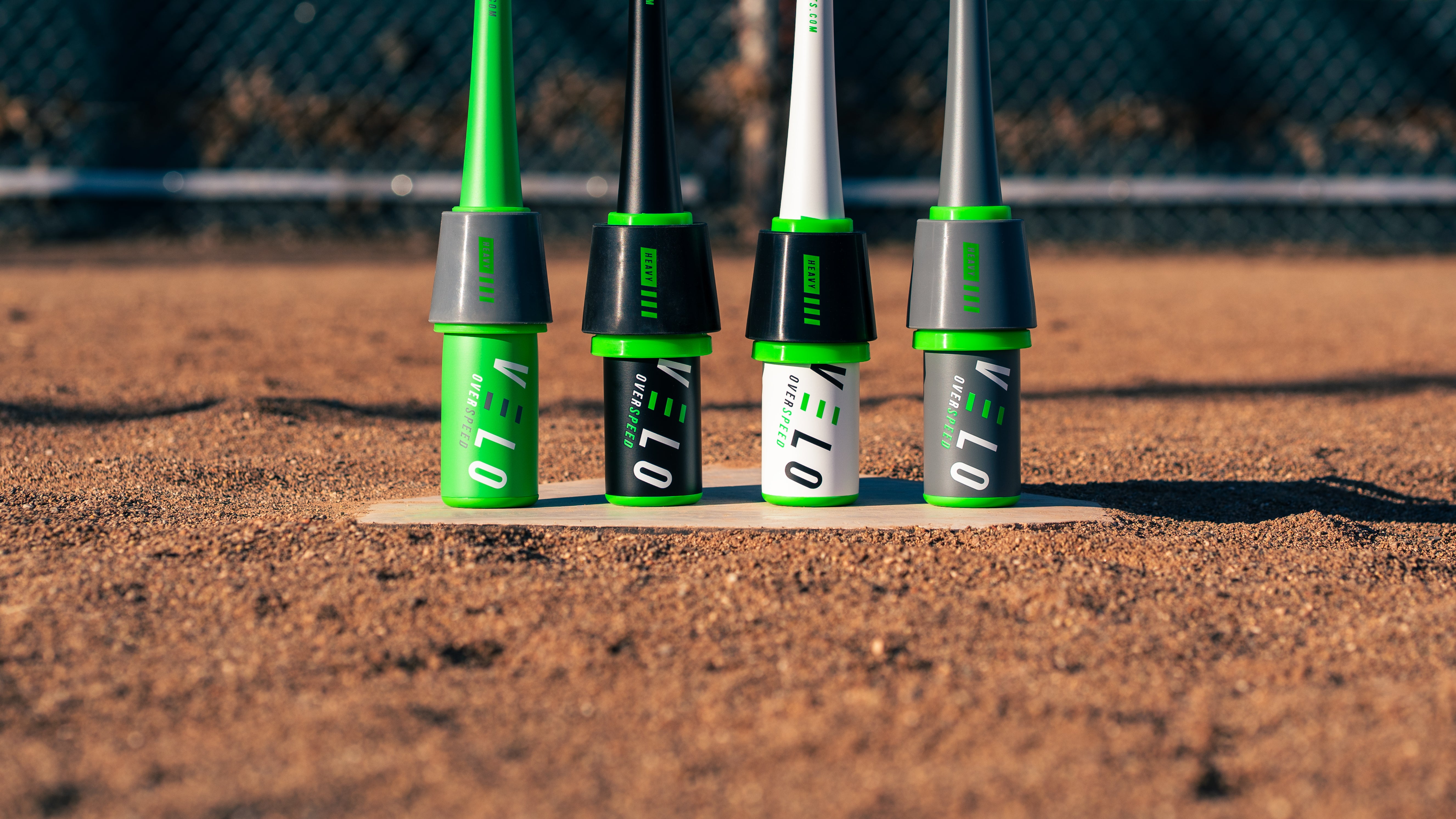 VELO Sports four main speed training bats (baseball, softball, all-star, youth) standing vertically on ball field home plate